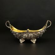 A Canadian silver bowl of gondola form with embossed floral decoration and a 9ct gilt gold interior,