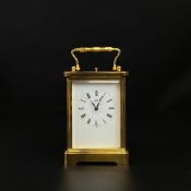 A Matthew Norman brass carriage clock having a swing handle above a moulded cornice, the enamelled