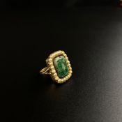 An early 19th century yellow metal ring inset with malachite surrounded by pearls and inscribed with