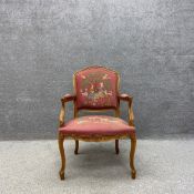 A 19th century French style open armchair having a carved frame surrounding a needlework upholstered