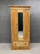 A Victorian pine wardrobe with simple angled cornice above a mirrored door over a single drawer on a