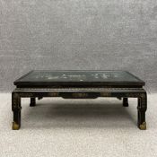 A 20th century Chinese lacquered coffee table inset with soapstone figures to the top under plate