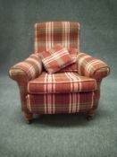 An early 20th century armchair with a shaped back and rolled armrests in a tartan fabric