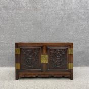 A 20th century Chinese hardwood cabinet with a traditional brass lock and hinges having panelled