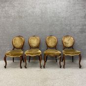 A set of four Victorian walnut balloon back dining chairs each having a scrolling cresting carved