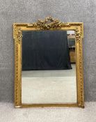 A late 19th century French gilt and gesso overmantel mirror having an ornate floral cresting with