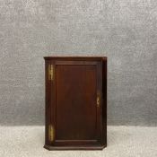 A Georgian wall mounted mahogany corner cabinet with a brass escutcheon and hinges. H.95 W.66 D.