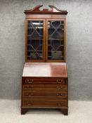 A Georgian style mahogany bureau bookcase having a shaped pediment above two glazed doors, the lower