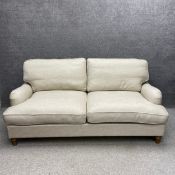 A contemporary two seater Howard style sofa bed upholstered in an oat calico raised on turned