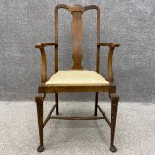 A C.1900 oak carver armchair having a carved top rail over a shaped splat with two scrolling