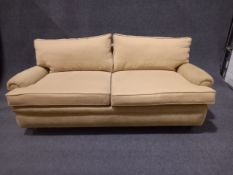 A contemporary Howard style sofa with scrolled arms raised on turned tapering mahogany supports
