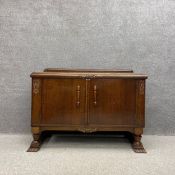 A 1950's Art Deco style oak sideboard having a moulded top over two cabinet doors with carved