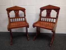 A pair of late 19th century Arts and Crafts oak hall chairs each having a carved pediment above a