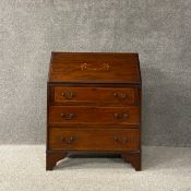 A Edwardian mahogany bureau having a marquetry inlaid fall front opening on to a fitted interior