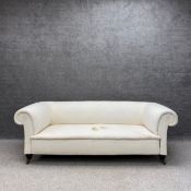 A Victorian three seater Chesterfield sofa upholstered in an off white calico with a scrolled back
