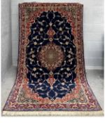 A large Persian silk Qum carpet with a central medallion surrounded by scrolling foliate
