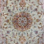 A silk Tabriz rug having a central medallion in dusty pink surrounded by scrolling foliate designs