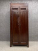 A 20th century Eastern hardwood wardrobe having a pair of carved panelled doors opening on to an