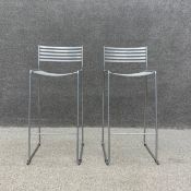 A pair of Aero metal counter stools each having a slatted back and seat raised on slender trestle