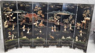 A mid 20th century Chinese lacquer and carved soapstone six panel folding screen depicting a