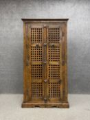 A mid 20th century Eastern hardwood pantry cupboard having a carved cornice over two open lattice