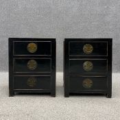 A pair of 20th century black lacquered and distressed Chinese bedside chests of three short brass