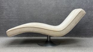 A mid century chaise longue of curvilinear form in a cream textured chenille upholstery raised on