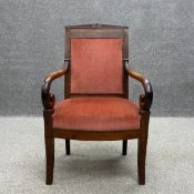 A 19th century French Empire mahogany elbow chair having a carved pediment above a dusty pink