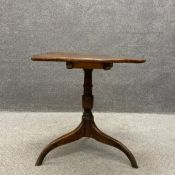 A Georgian elm tilt top occasional table having an undulating circular top raised on a turned