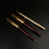 A collection of three pens to include an English burgundy Parker 51 fountain pen with a rolled