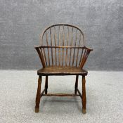 An early 19th century elm stick back Windsor armchair having a curved hoop back with outswept arms
