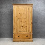 A Victorian pine wardrobe having a moulded cornice above a single panelled door over a single drawer