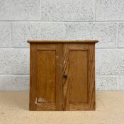 A small early 20th century pine table top cabinet having a rectangular top with a moulded edge
