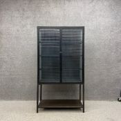 A contemporary industrial style iron cabinet on stand having two laminated mesh glass doors and