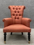 A 19th century button back library armchair having a splayed scrolling back with curved arms over