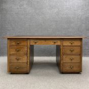 An early 20th century oak and elm pedestal desk having a gilt tooled oxblood leather top over an
