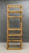 A mid century cane etagere open shelving unit with six inset plate glass shelves of varying heights.