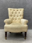 A 19th century button back library armchair having a tapered back with scrolling arms over a