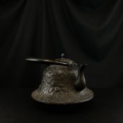 A late 19th century Japanese iron tetsubin or kettle with a curved swing handle over a lidded bell