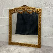 A Neoclassical 19th century style giltwood mirror having a profusely carved pediment with a floral