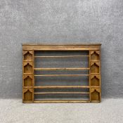 A 19th century pine wall mounted delft or plate rack having a moulded cornice over three long open