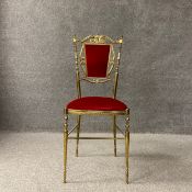A brass salon chair having a shaped scrolling openwork back with an iron red velvet upholstered