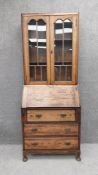 An early 20th century oak bureau bookcase having two cabinet doors with shaped glazed apertures