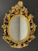 A contemporary Rococo style composite oval mirror with allover scrolling openwork decoration. (