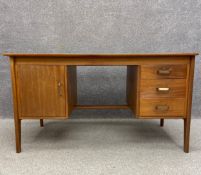 A 1960's teak desk by Gordon Russell having a rectangular top over a cabinet and three short drawers