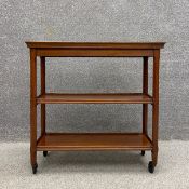 An Edwardian walnut trolley having a thumb moulded rectangular tray top over two lower shelves