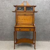 A C.1900 ash Arts and Crafts escritoire having a waterfall superstructure with a shaped and carved