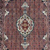 A wool Persian Bijar carpet having a central biscuit medallion with scrolling designs surrounded