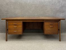 A mid century Danish teak executive partners desk in the style of Arne Vodder having a book