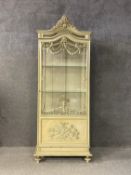 A 19th century French painted vitrine or display cabinet having an arched pediment with a carved